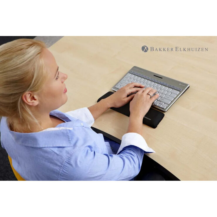 Women typing using a Trapezium Ergo Wrist Rest Compact, sitting on a office desk. Ergonomic Accessory to help improve natural posture.
