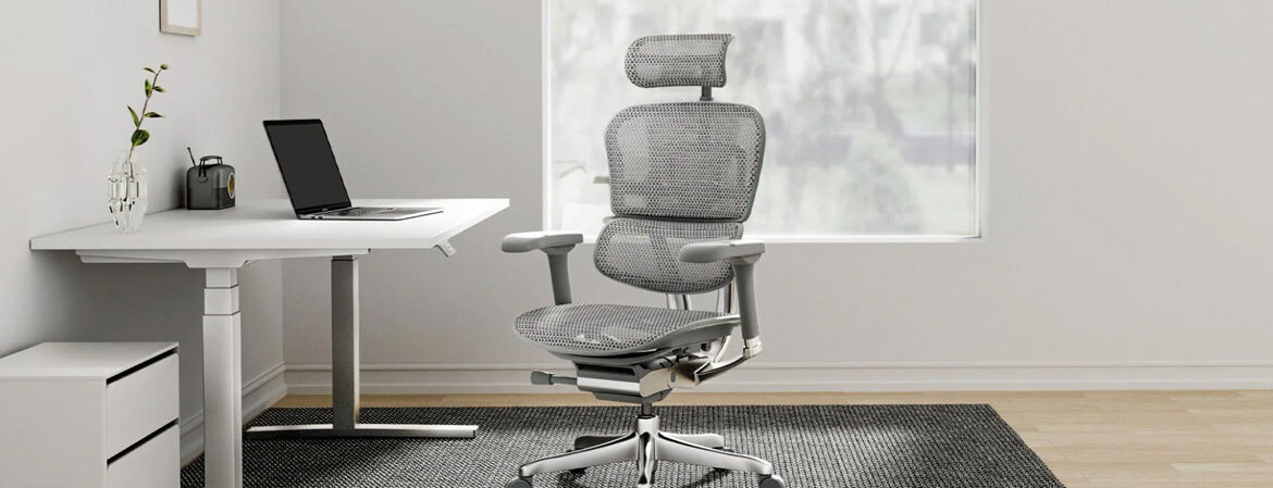 Lifestyle image of a sit-stand desk and ergonomic high back, mesh chair with headrest, adjustable arms and chrome 5 star base.