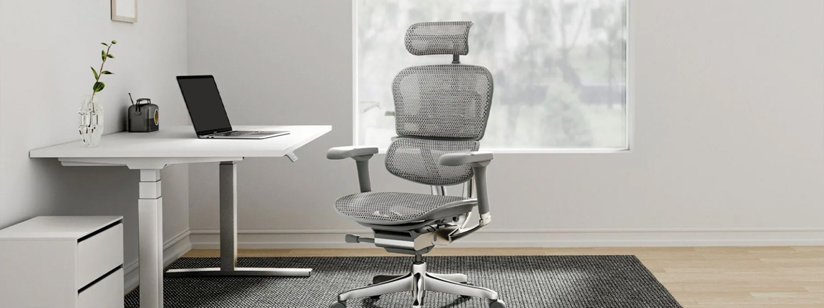 Lifestyle image of a sit-stand desk and ergonomic high back, mesh chair with headrest, adjustable arms and chrome 5 star base.