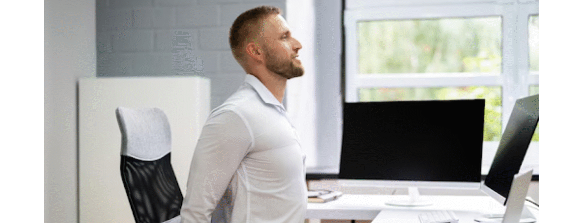 man stretching his back sitting at his desk
