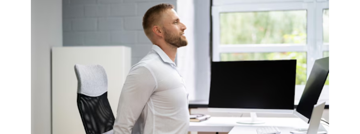 man stretching his back sitting at his desk