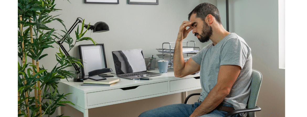 man working from home sat at his desk feeling stressed
