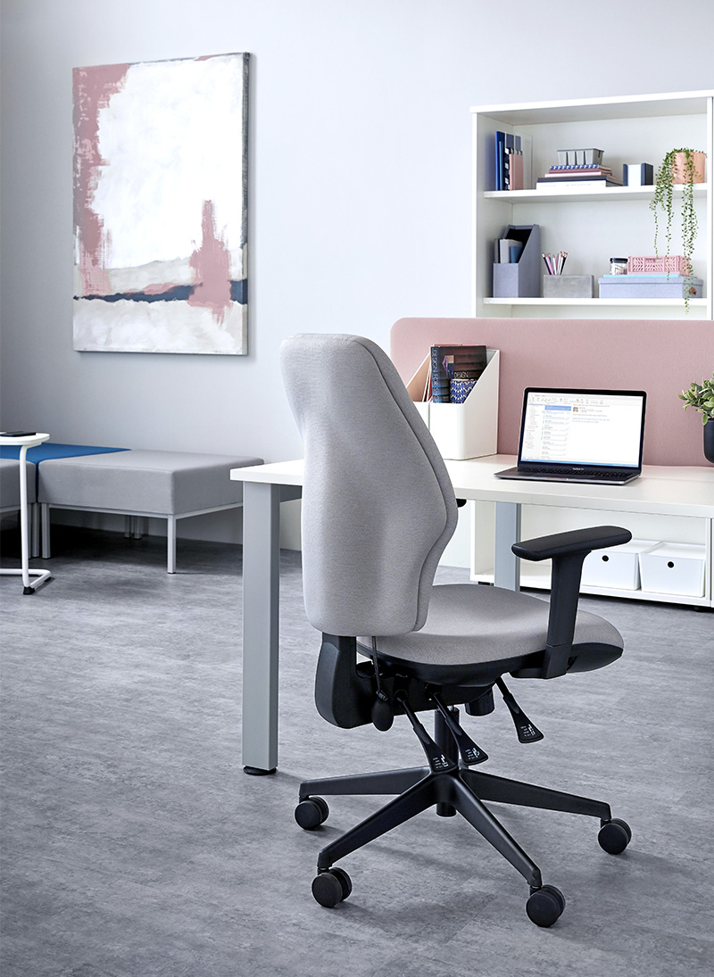 Orthopaedica 200 series task chair by Torasen. The chair is in an office and fully upholstered in grey fabric with black components including black adjustable arms, mechanism levers and 5 star castor base.