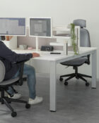 Ergonomic Task Chair with a Built In Headrest in an office workstation set-up. The chair is fully upholstered in a grey fabric with black accessories including arms and 5 star castor base. Torasen 100 Series Range